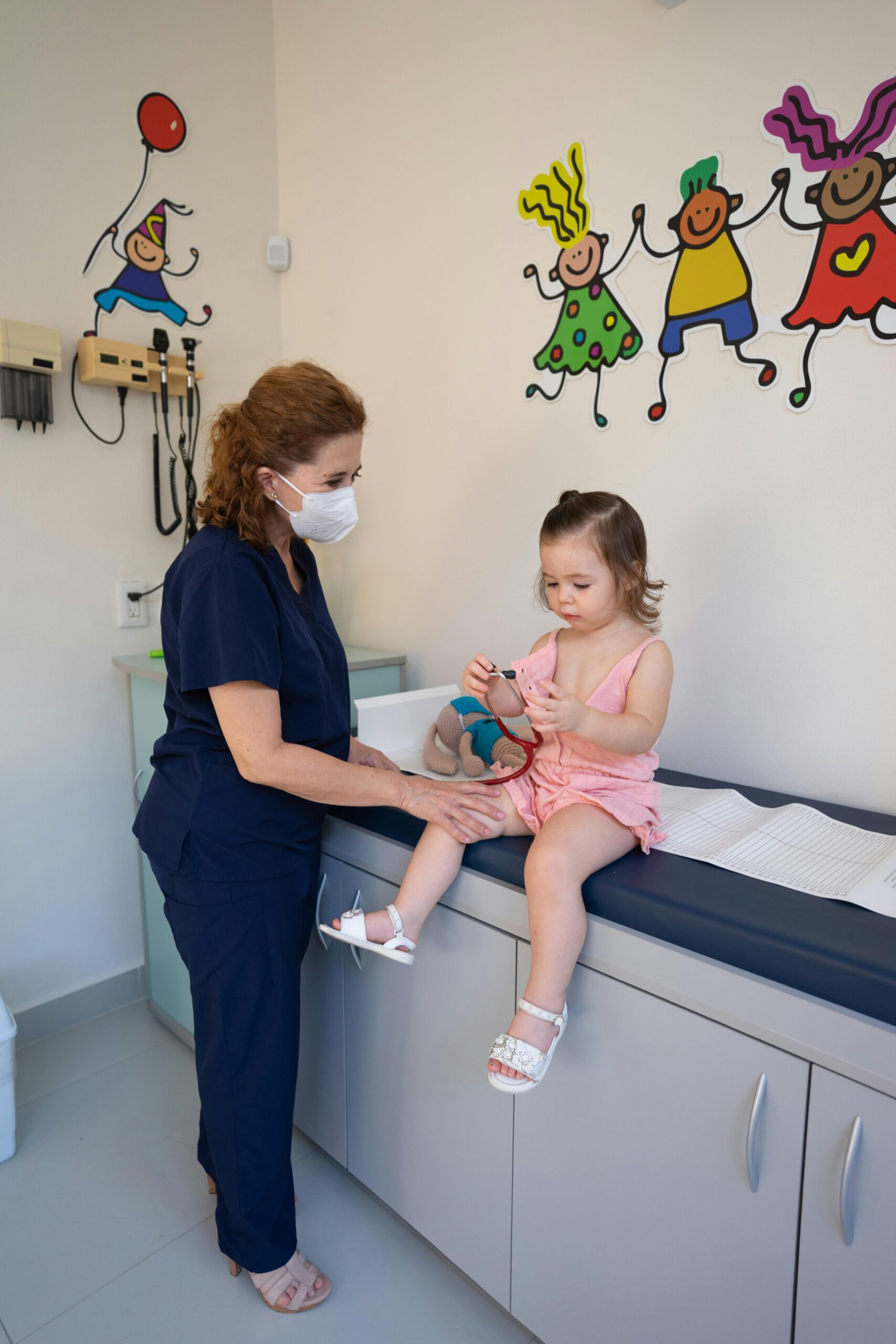 A child is examined by a nurse in a pediatrician's office, emphasizing gentle healthcare.